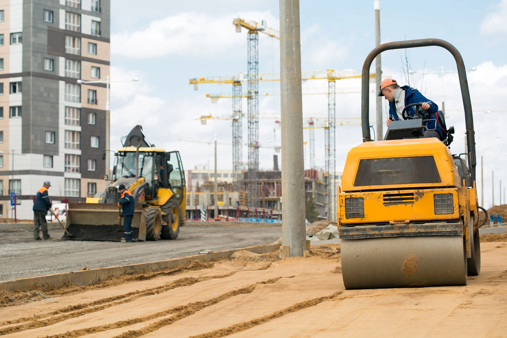 Chantier de construction urbain avec ouvriers en équipements de sécurité opérant des engins de terrassement