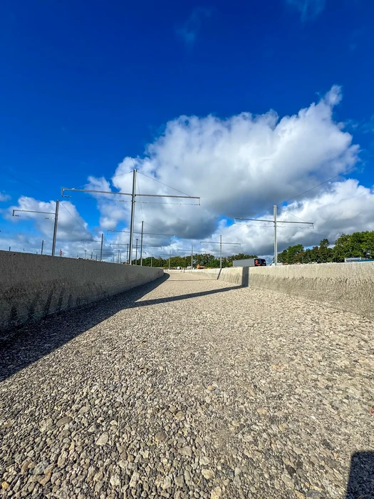 Chantier de construction routière en cours, voie en gravier non revêtue avec murs de soutènement en béton de chaque côté