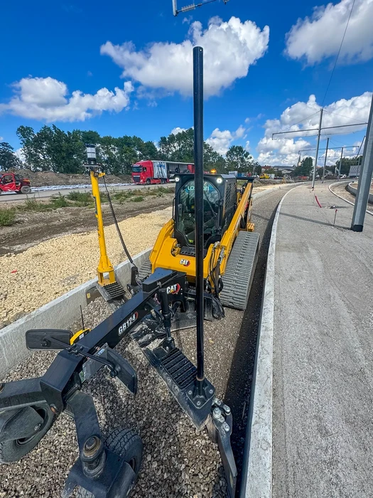 Chantier de construction extérieur avec pelleteuse jaune Cat équipée d'un marteau-piqueur hydraulique positionnée sur voie en béton