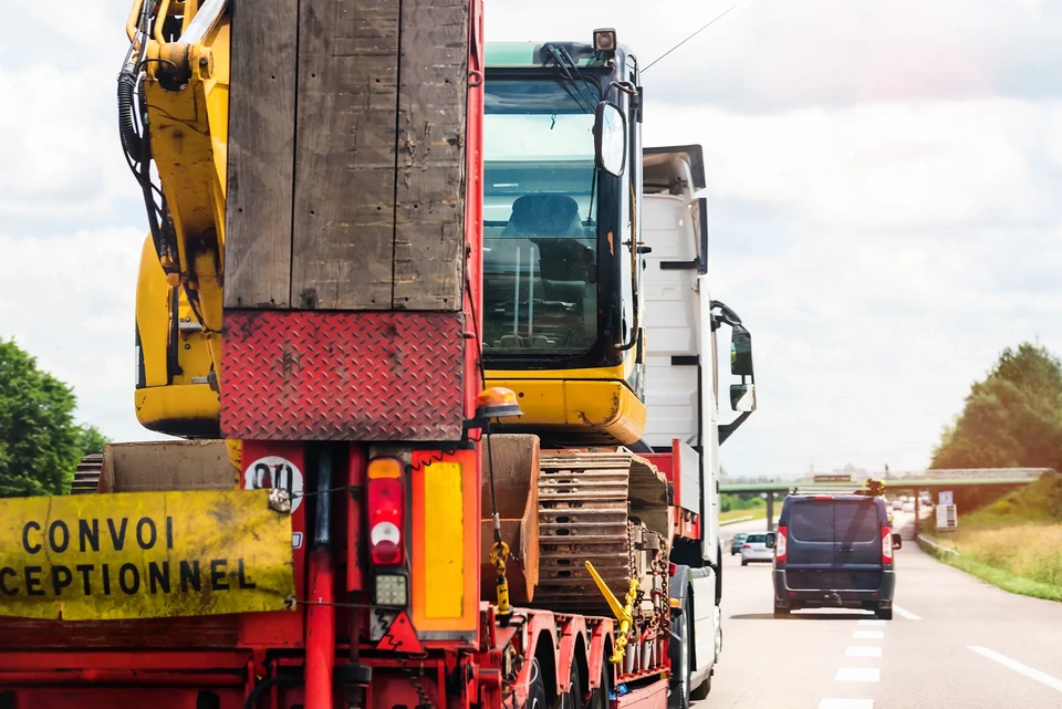 Camion semi-remorque blanc en mouvement sur route, ciel bleu nuageux, paysage rural en arrière-plan avec effet de vitesse visible au sol et végétation