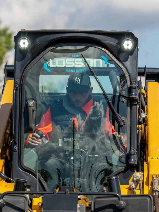 Scène industrielle intérieure avec ouvrier en équipement de sécurité supervisisant opération de levage