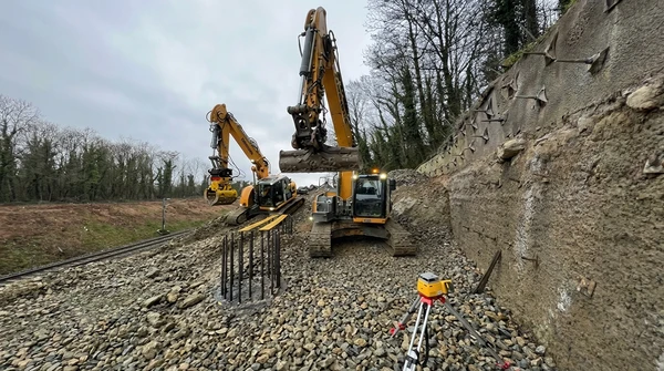 Chantier de construction ext&eacute;rieur au coucher du soleil avec machine de forage hydraulique jaune et rouge en activit&eacute;