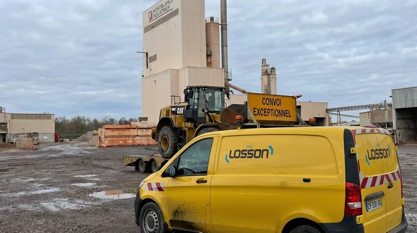 Camion semi-remorque bleu circulant sur route goudronn&eacute;e &agrave; travers paysage rural verdoyant